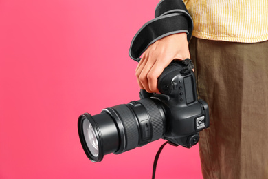 Professional photographer with modern camera on pink background in studio, closeup. Space for text