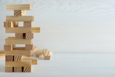 Jenga tower made of wooden blocks on white table, space for text
