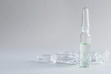 Pharmaceutical ampoules with medication on light grey background. Space for text