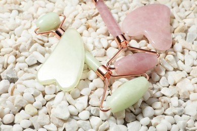 Photo of Quartz gua sha tools and face rollers on white stones, closeup