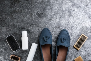 Stylish footwear with shoe care accessories on grey stone table, flat lay. Space for text