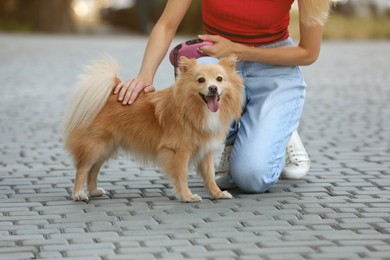 Young woman with her cute dog on city street, closeup