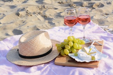 Photo of Glasses with rose wine and snacks for beach picnic on sand outdoors
