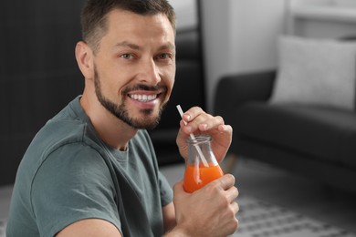 Man holding bottle of delicious juice at home