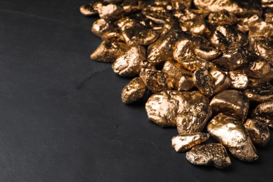 Pile of gold nuggets on black table, space for text