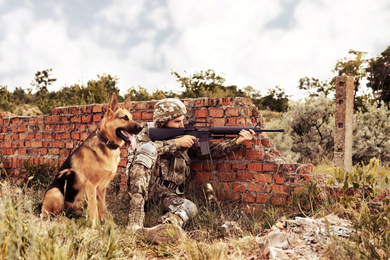 Man in military uniform with German shepherd dog at firing range