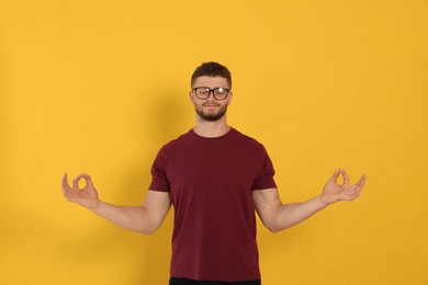 Young man meditating on orange background. Zen concept