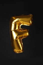 Photo of Golden letter F balloon on black background