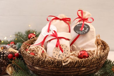 Photo of Bags with gifts in basket and festive decor on table, closeup. Christmas advent calendar