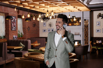 Young business owner talking on phone in his cafe