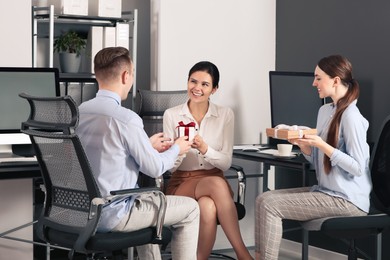 Photo of Colleagues presenting gifts to man in office
