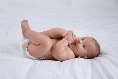 Cute baby in dry soft diaper on white bed
