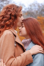 Photo of Portrait of beautiful young redhead sisters in park on autumn day