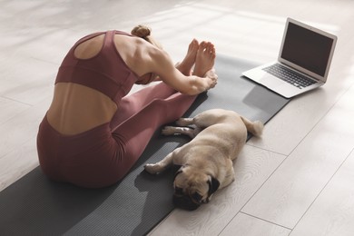 Woman with dog following online yoga class at home, back view