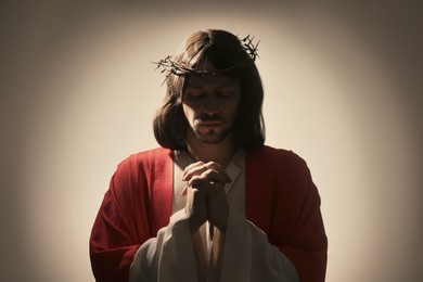 Jesus Christ with crown of thorns praying on light background