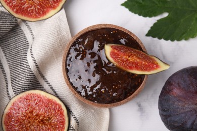 Photo of Bowl of tasty sweet fig jam and fruits on white marble table, flat lay