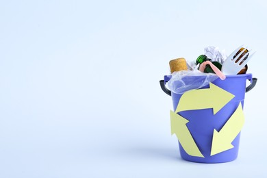 Bucket with recycling symbol full of garbage on white background. Space for text