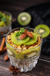 Photo of Delicious dessert with kiwi muesli and almonds on wooden table, closeup