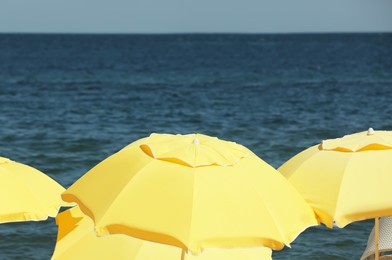 Yellow beach umbrellas near sea on sunny day