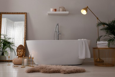 Bathroom interior with golden Buddha sculpture and modern white tub