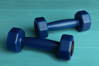 Photo of Blue vinyl dumbbells on turquoise wooden table