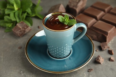 Cup of delicious hot chocolate with fresh mint on grey table