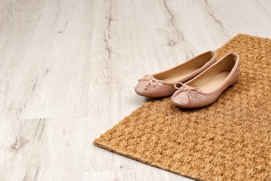 New clean doormat with shoes on floor. Space for text