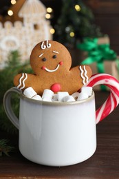 Photo of Gingerbread man in cup on wooden table, closeup