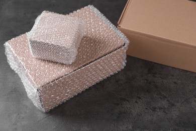 Photo of Cardboard boxes with bubble wrap on dark grey table
