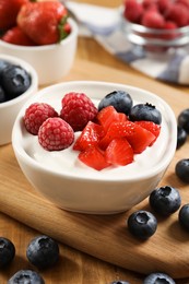 Photo of Delicious yogurt served with berries on wooden table, closeup