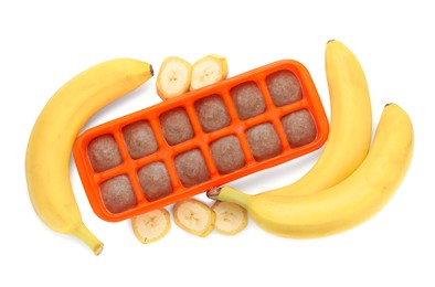 Banana puree in ice cube tray and ingredients on white background, top view. Ready for freezing