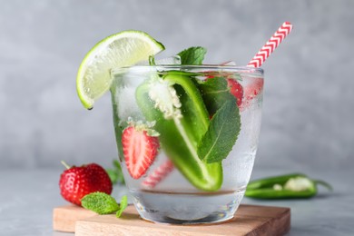 Spicy cocktail with jalapeno, strawberry, lime and mint on light grey table, closeup