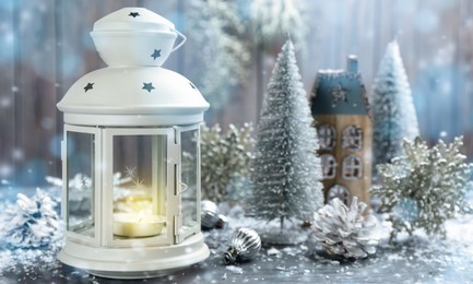 Christmas lantern with burning candle and festive decor on wooden background