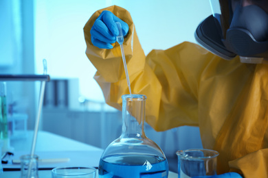 Scientist in chemical protective suit working at laboratory, closeup. Virus research