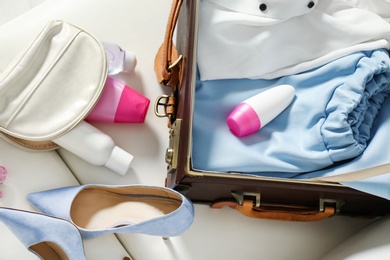 Vintage suitcase with deodorants and clothes indoors, closeup view