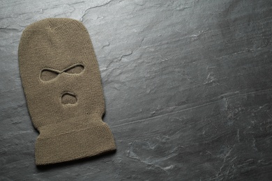 Photo of Beige knitted balaclava on black table, top view. Space for text