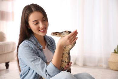 Young woman with her boa constrictor at home. Exotic pet