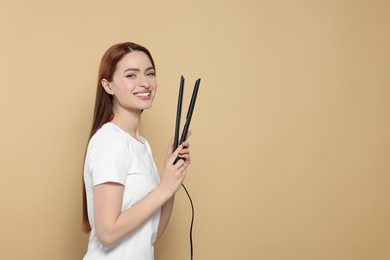 Photo of Beautiful woman with hair iron on beige background, space for text