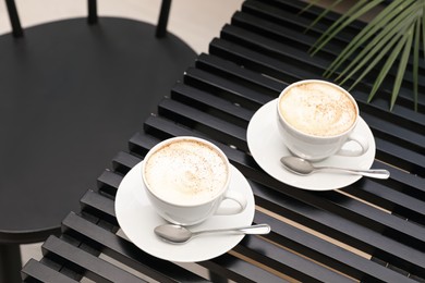 Photo of Ceramic cups of aromatic coffee with foam on wooden table in cafe