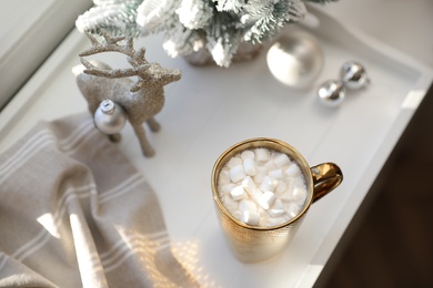 Golden cup of cocoa and Christmas decor on window sill indoors, above view