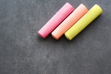 Colorful chalk sticks on black surface, flat lay. Space for text