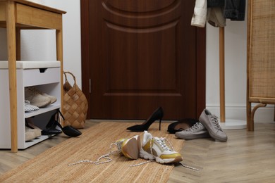 Different stylish shoes scattered on floor in hall