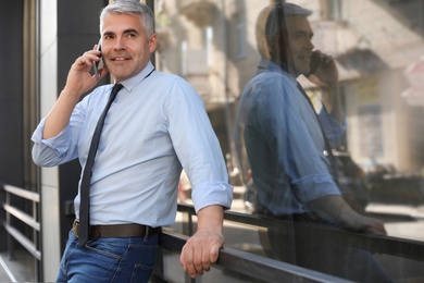 Handsome businessman talking by mobile phone in city