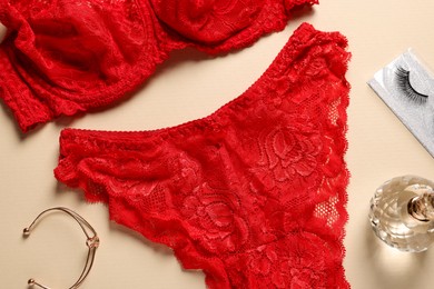 Photo of Elegant red women's underwear, bracelet and perfume on beige background, flat lay