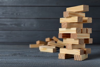 Jenga tower made of wooden blocks on grey table, space for text