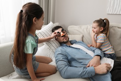 Photo of Cute little children putting funny glasses on father while he sleeping at home