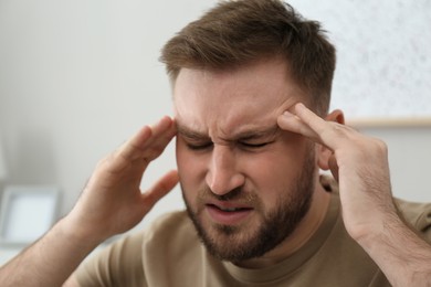 Young man suffering from migraine at home