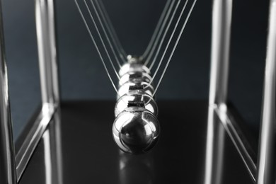 Photo of Newton's cradle on dark background, closeup. Physics law of energy conservation