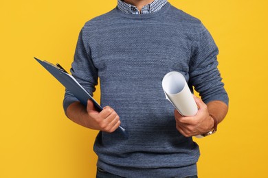 Professional engineer with clipboard and draft on yellow background, closeup