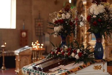 Ecclesiastical icon, cross and flowers on altar in church. Baptism ceremony